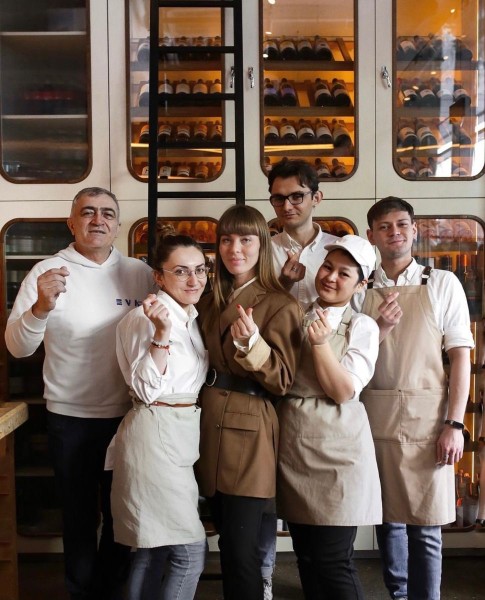 Photo of a food & beverage team in front of a wine fridge