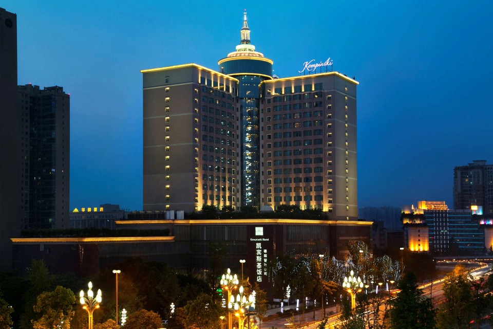 Photo of an hotel's restaurant overlooking a city by night with large windows  