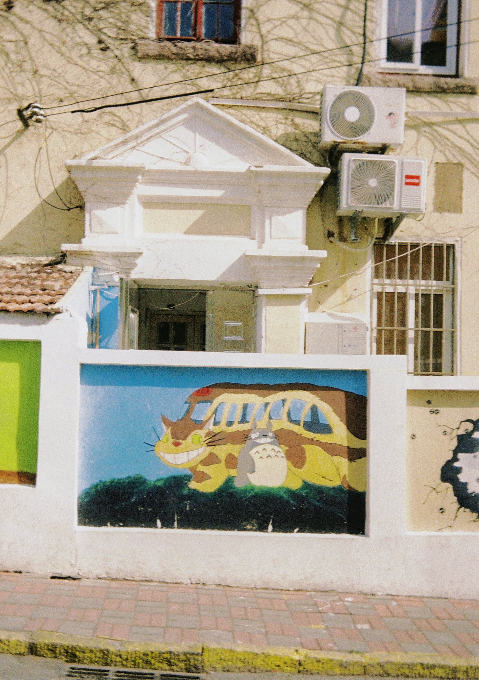 Picture of a painting of My Neighboor Totoro's catbus on a wall alongside Totoro. Two characters from Ghibli studios